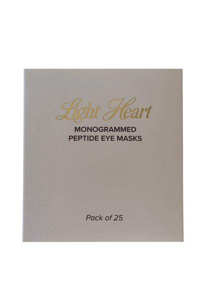 Pack of 25 monogrammed peptide eye masks by Light Heart on a beige background