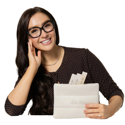 Lash technician smiling and holding a Light Heart Lashes cream branded supply bag filled with lash extension products